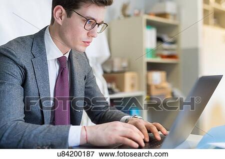 Stock Photo - Man using laptop in office. Fotosearch