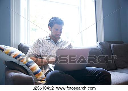 Man using laptop on sofa View Large Photo Image Stock Image - Man using laptop on sofa. Fotosearch