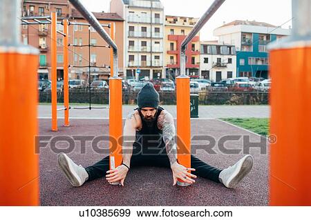 Stock Photo - Man using parallel bars in outdoor gym. Fotosearch