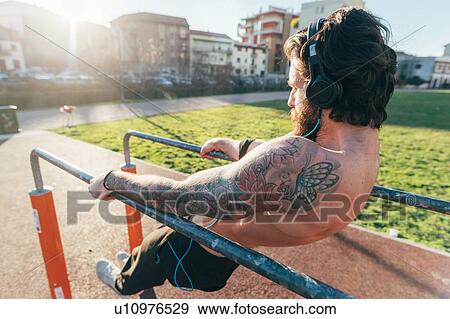 Stock Photo - Man using parallel bars in outdoor gym. Fotosearch