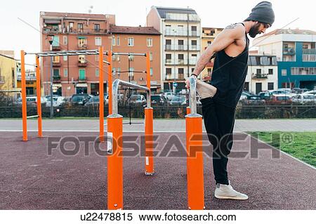 Stock Photography - Man using parallel bars in outdoor gym. Fotosearch