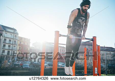 Man using push up bar in outdoor gym View Large Photo Image Stock Photograph - Man using push up bar in outdoor gym. Fotosearch