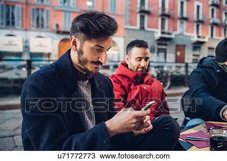 Man using smartphone at outdoor cafe, Milan, Italy View Large Photo Image Stock Image - Man using smartphone at outdoor cafe, Milan, Italy. Fotosearch