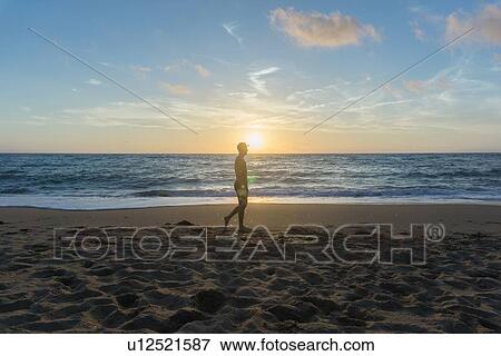 Man walking on beach at sunset View Large Photo Image Stock Photo - Man walking on beach at sunset. Fotosearch