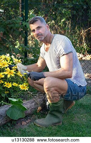 Stock Photo - Man with trowel by flower bed. Fotosearch