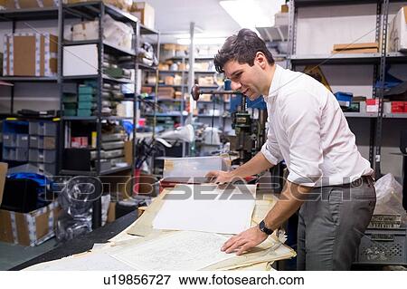 Man working on charts and plans in warehouse View Large Photo Image Stock Photo - Man working on charts and plans in warehouse. Fotosearch