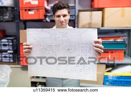 Stock Photography - Man working on charts and plans in warehouse. Fotosearch