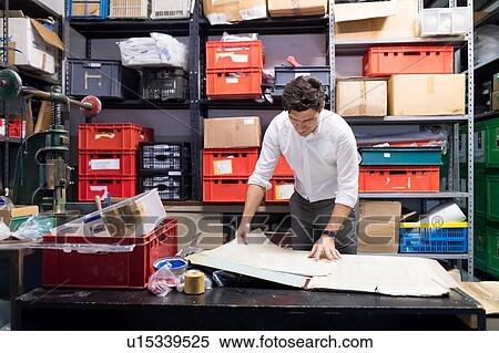 Man working on charts and plans in warehouse View Large Photo Image Stock Photography - Man working on charts and plans in warehouse. Fotosearch