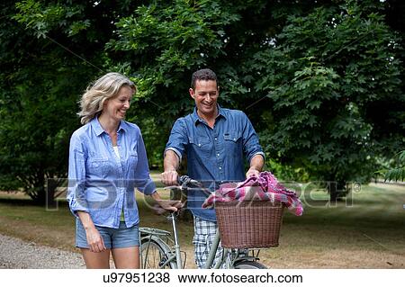 Mature couple pushing bicycle on rural road View Large Photo Image Stock Photo - Mature couple pushing bicycle on rural road. Fotosearch