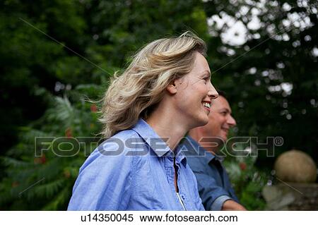 Stock Photography - Mature couple smiling while strolling in garden. Fotosearch
