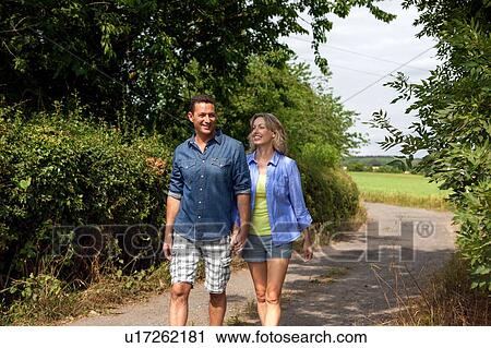 Stock Image - Mature couple strolling along rural road. Fotosearch