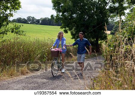 Picture - Mature couple strolling and cycling on rural road. Fotosearch
