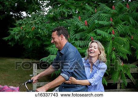 Mature woman riding pillion on bicycle on rural road View Large Photo Image Stock Image - Mature woman riding pillion on bicycle on rural road. Fotosearch