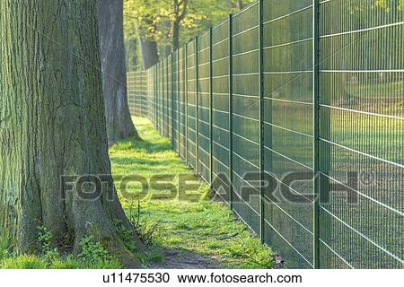 Stock Image - Metal fence in urban park.. Fotosearch