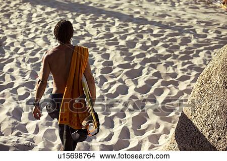 Mid adult male surfer carrying surfboard on beach, rear view, Camps Bay Beach, Cape Town, South Africa View Large Photo Image Picture - Mid adult male surfer carrying surfboard on beach, rear view, Camps Bay Beach, Cape Town, South Africa. Fotosearch