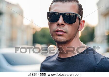 Stock Photography - Mid adult man wearing sunglasses, portrait. Fotosearch