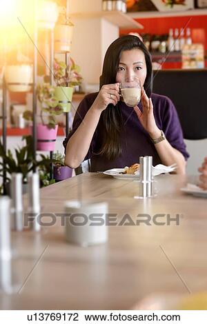 Mid adult woman drinking coffee in cafe View Large Photo Image Stock Image - Mid adult woman drinking coffee in cafe. Fotosearch