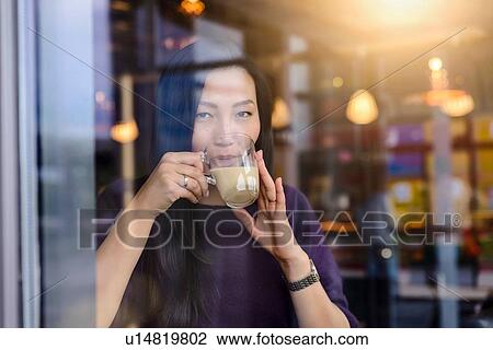 Mid adult woman drinking coffee in cafe window seat, portrait View Large Photo Image Stock Image - Mid adult woman drinking coffee in cafe window seat, portrait. Fotosearch