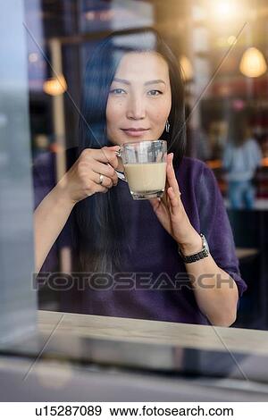 Mid adult woman with coffee looking out from cafe window seat, portrait View Large Photo Image Stock Photo - Mid adult woman with coffee looking out from cafe window seat, portrait. Fotosearch