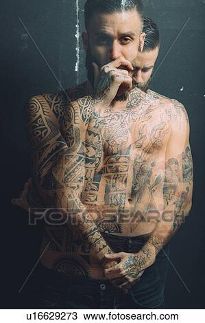 Stock Image - Multiple exposure of bare chested young man, covered in tattoos, pensive, worried expressions. Fotosearch