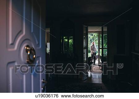 Stock Photograph - Open doorway, man and dog in background. Fotosearch