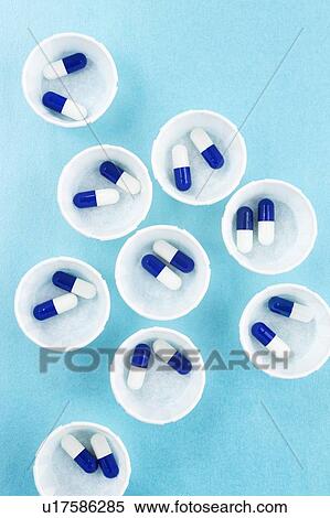 Stock Photography - Paper medicine pots with blue and white capsules.. Fotosearch