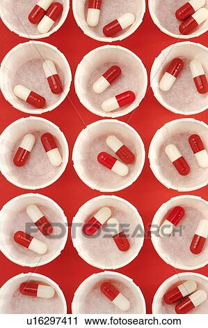 Stock Image - Paper medicine pots with red and white drug capsules.. Fotosearch