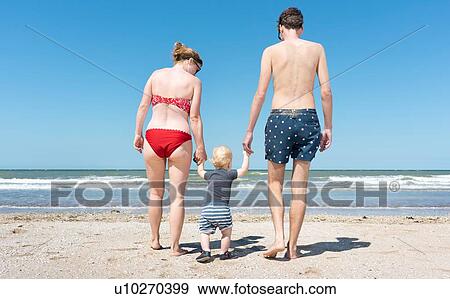Stock Photo - Parents walking with toddler on beach. Fotosearch