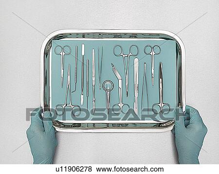 Stock Photo - Person holding tray with surgical equipment against a white background.. Fotosearch