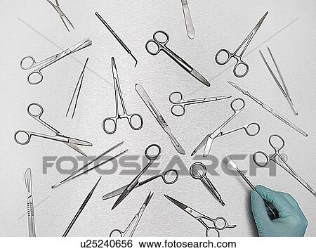 Stock Photograph - Person selecting surgical equipment against a grey background.. Fotosearch