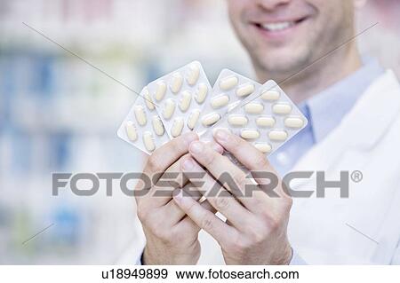 Stock Photo - Pharmacist holding blister packs in pharmacy.. Fotosearch