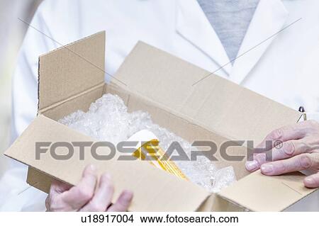 Picture - Pharmacist opening box containing medicine.. Fotosearch