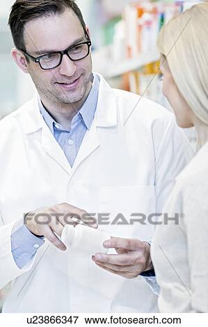 Stock Photo - Pharmacist showing medicine to woman in pharmacy.. Fotosearch