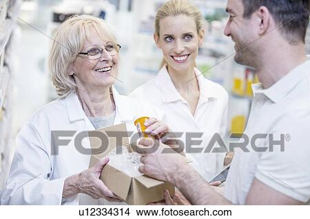 Picture - Pharmacist taking pill bottle from a box and giving it to customer.. Fotosearch