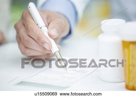 Stock Photo - Pharmacist writing prescription in pharmacy.. Fotosearch