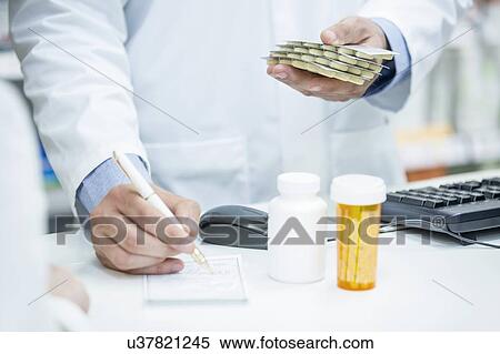 Stock Photography - Pharmacist writing prescription in pharmacy.. Fotosearch