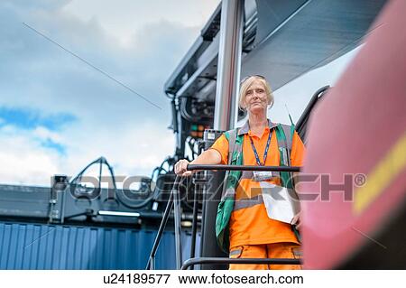 Stock Photo - Portrait of female container lift operator with shipping container in port. Fotosearch