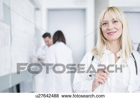 Stock Photo - Portrait of female doctor smiling towards camera.. Fotosearch