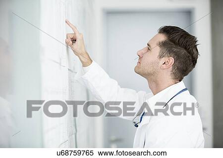 Stock Photography - Portrait of mature male doctor inspecting white board.. Fotosearch