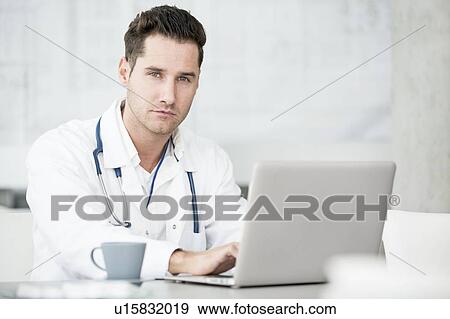 Stock Photo - Portrait of mature male doctor using laptop.. Fotosearch
