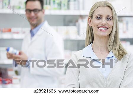 Stock Photography - Portrait of woman in pharmacy, with pharmacist in the background.. Fotosearch
