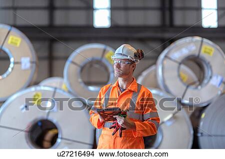Portrait of worker using digital tablet by rows of sheet steel in storage at port View Large Photo Image Picture - Portrait of worker using digital tablet by rows of sheet steel in storage at port. Fotosearch