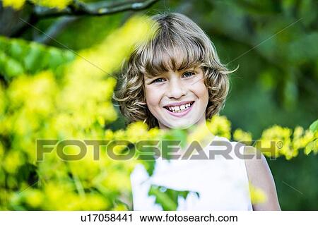 Portrait of young boy with yellow flowers in foreground, smiling. View Large Photo Image Stock Image - Portrait of young boy with yellow flowers in foreground, smiling.. Fotosearch