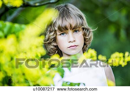 Stock Photo - Portrait of young boy with yellow flowers in foreground.. Fotosearch