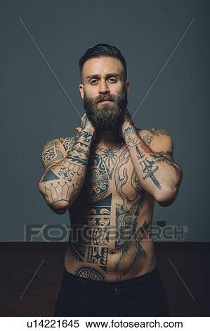 Portrait of young man with beard, bare chest covered in tattoos, hands behind neck View Large Photo Image Stock Photography - Portrait of young man with beard, bare chest covered in tattoos, hands behind neck. Fotosearch