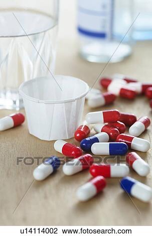 Red and white and blue and white drug capsules by a glass of water. View Large Photo Image Stock Image - Red and white and blue and white drug capsules by a glass of water.. Fotosearch