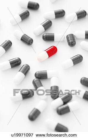 Red and white pill capsule surrounded by black and white pills scattered on a white background. View Large Photo Image Stock Photo - Red and white pill capsule surrounded by black and white pills scattered on a white background.. Fotosearch
