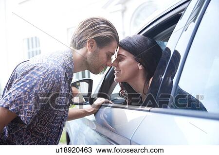 Stock Image - Romantic couple face to face through car window. Fotosearch