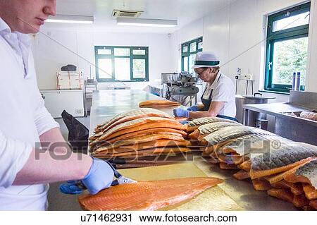 Stock Image - Salmon being prepared in smokehouse kitchen. Fotosearch