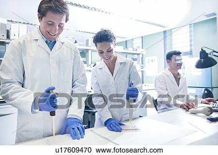 Stock Image - Scientists using pipettes in the laboratory.. Fotosearch